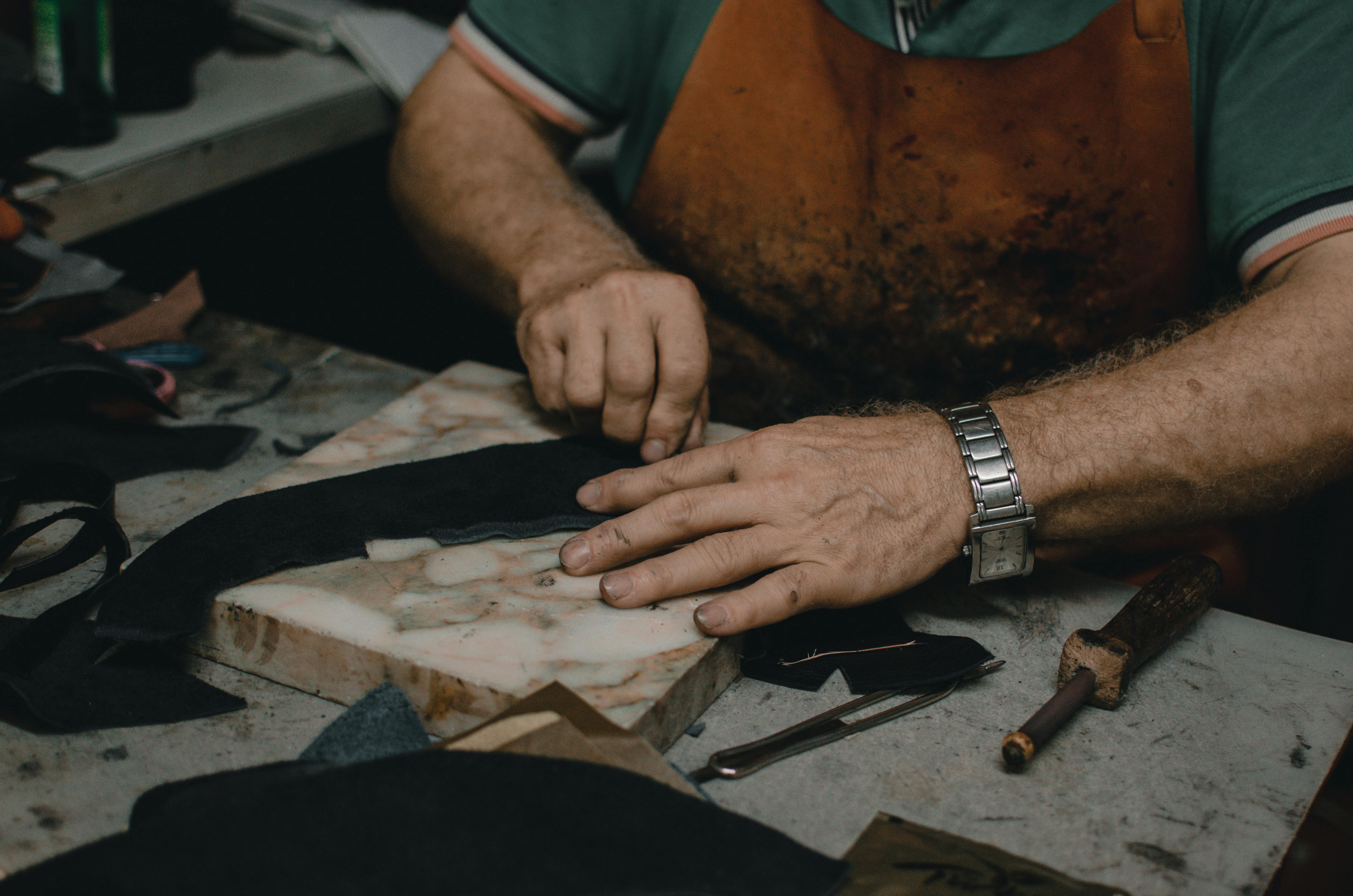 Leather craftsman hand-finishing collar straps at YL Leather workshop Istanbul Turkey